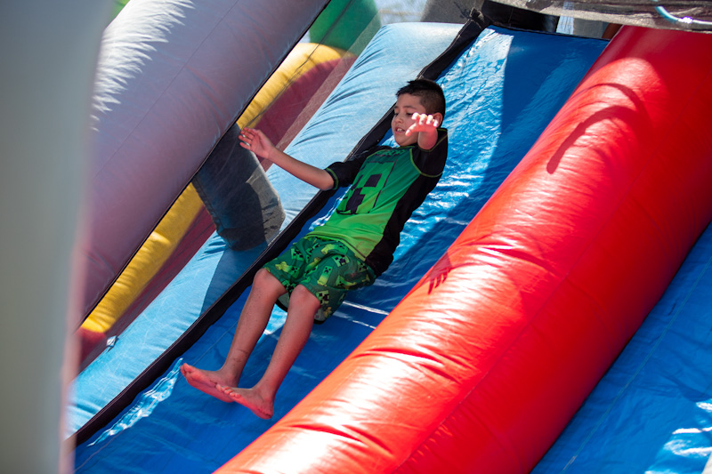 A boy goes down a bouncy house waterslide
