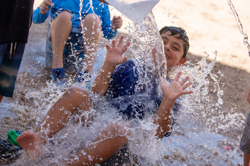 A boy smiles as he gets splashed with water