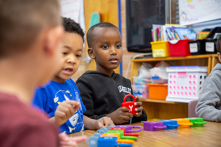Two young boys play with colorful letter blocks