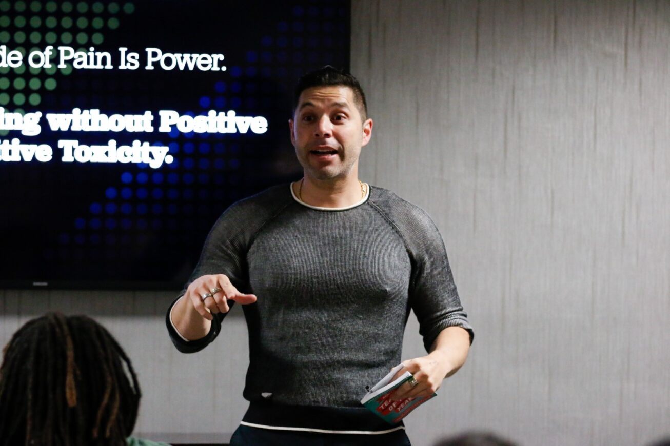 A man in a gray shirt delivers his presentation for the audience
