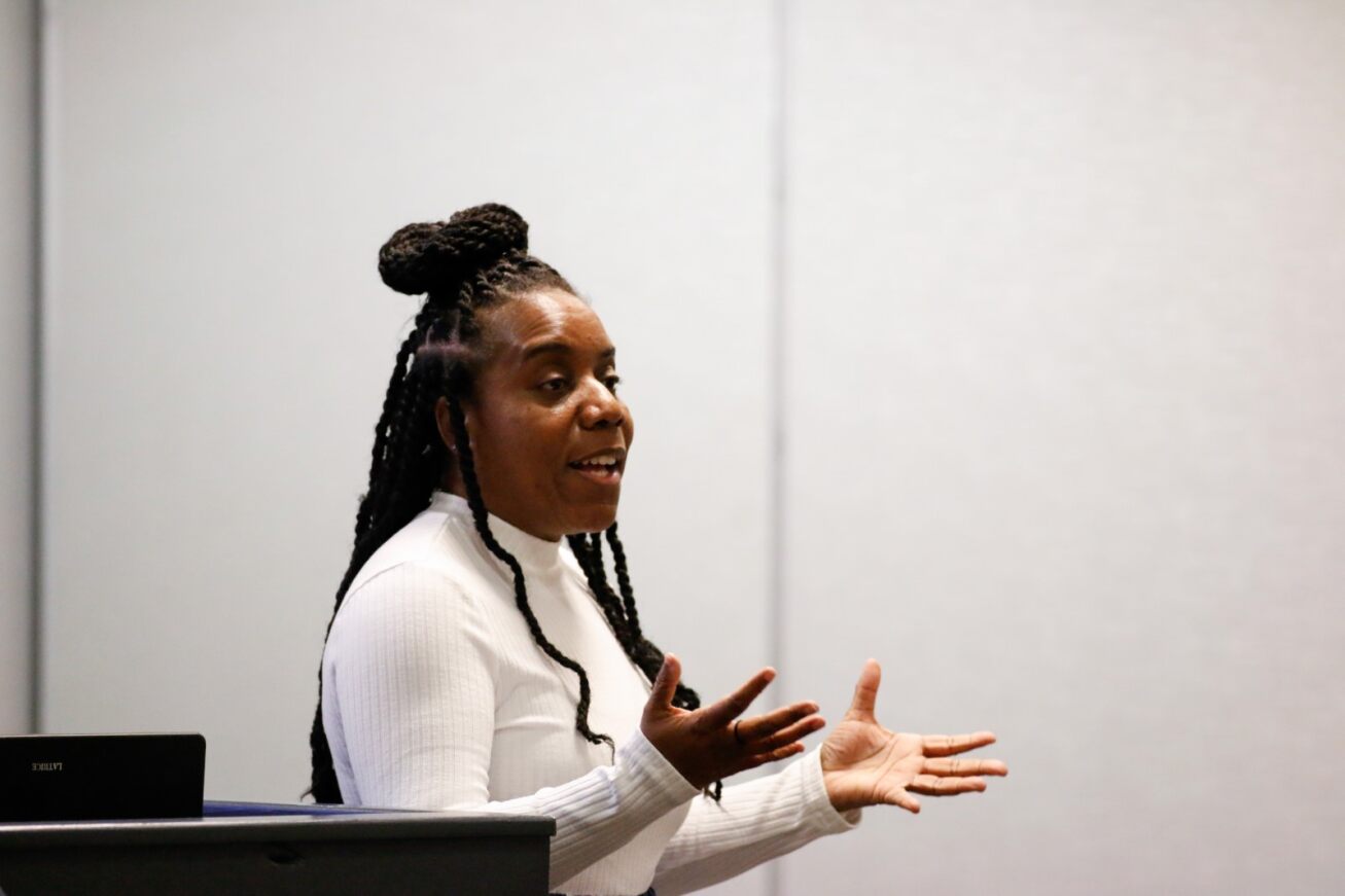 A woman in a white shirt delivers her presentation to the audience