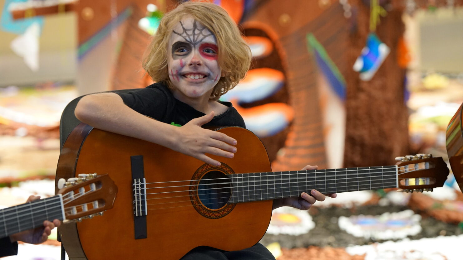 A boy smiles while playing guitar. 