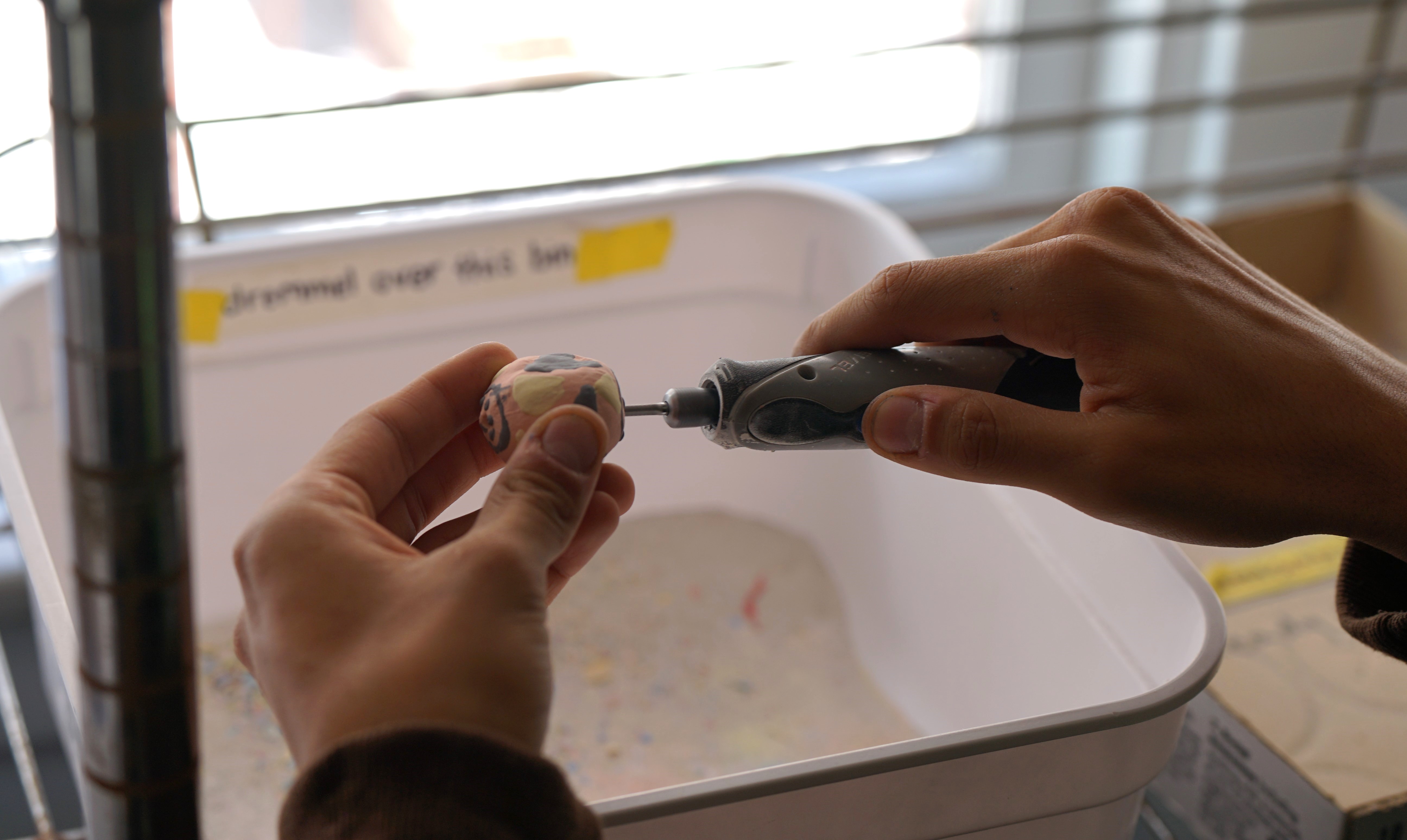 Closeup of a student working on a clay figurine