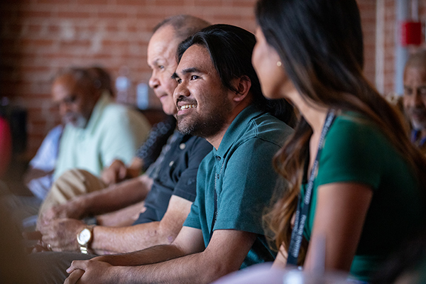 Three men and a woman sit in a row listening to a presentation