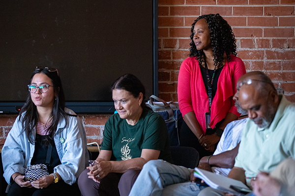 Three women and two men in a row listening to a presentation