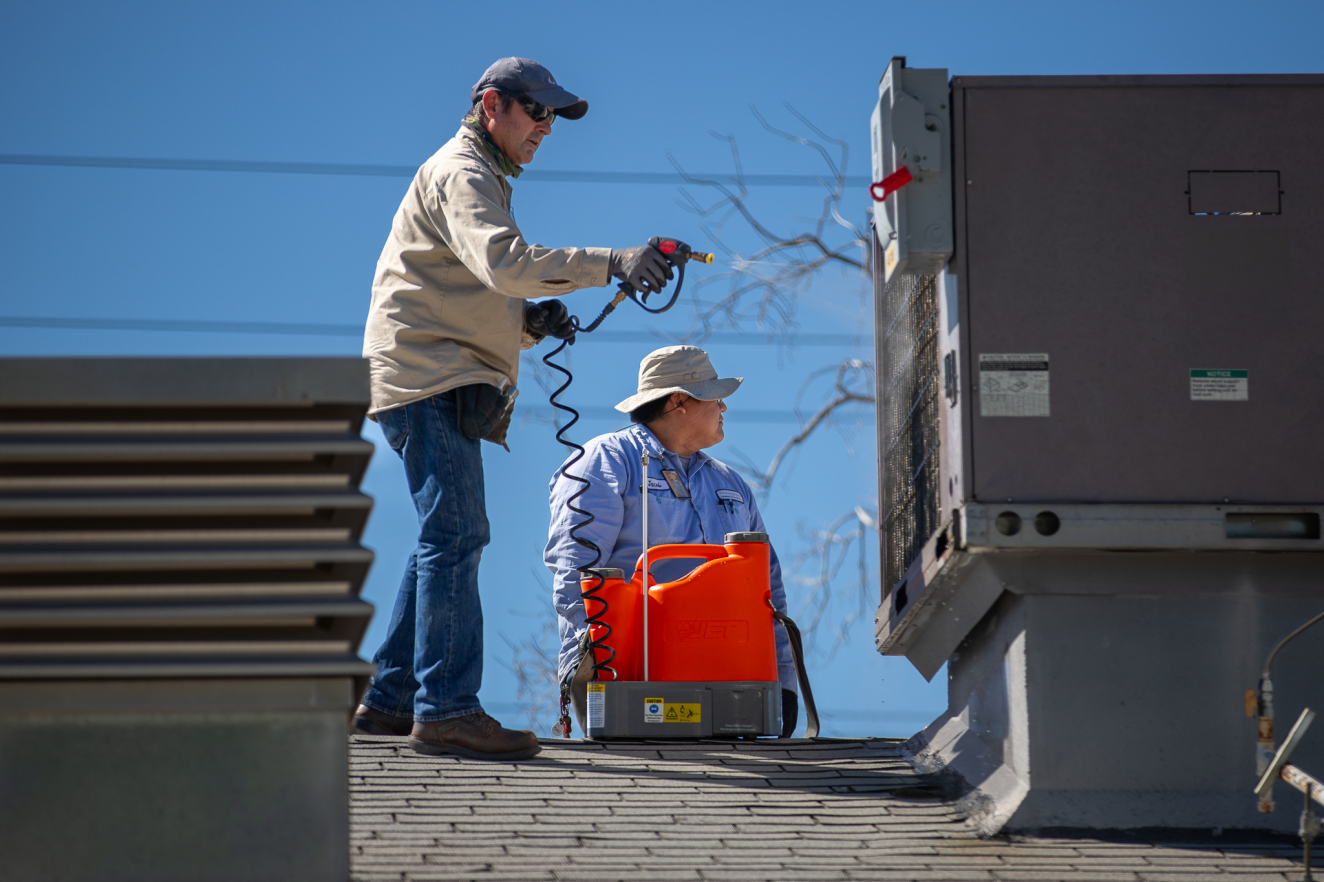 Martin Gonzalez and Jacob Smith work on an air conditioning unit at a school.