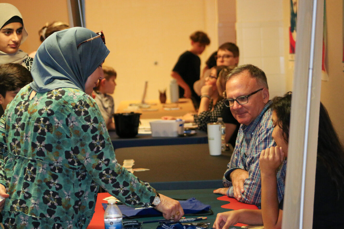 A woman browses a table staffed by two employees.