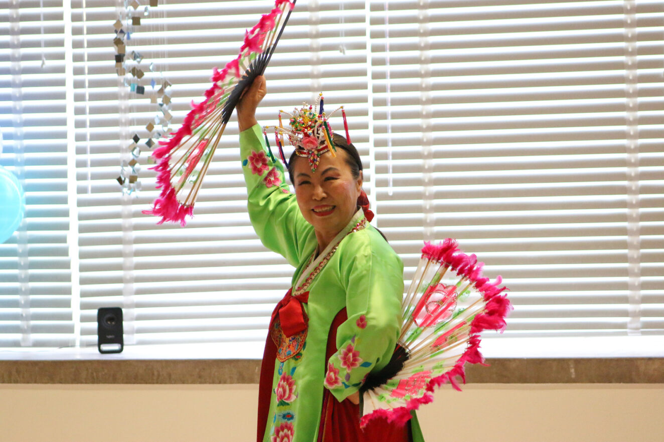 A woman smiles while dancing in a traditional costume.