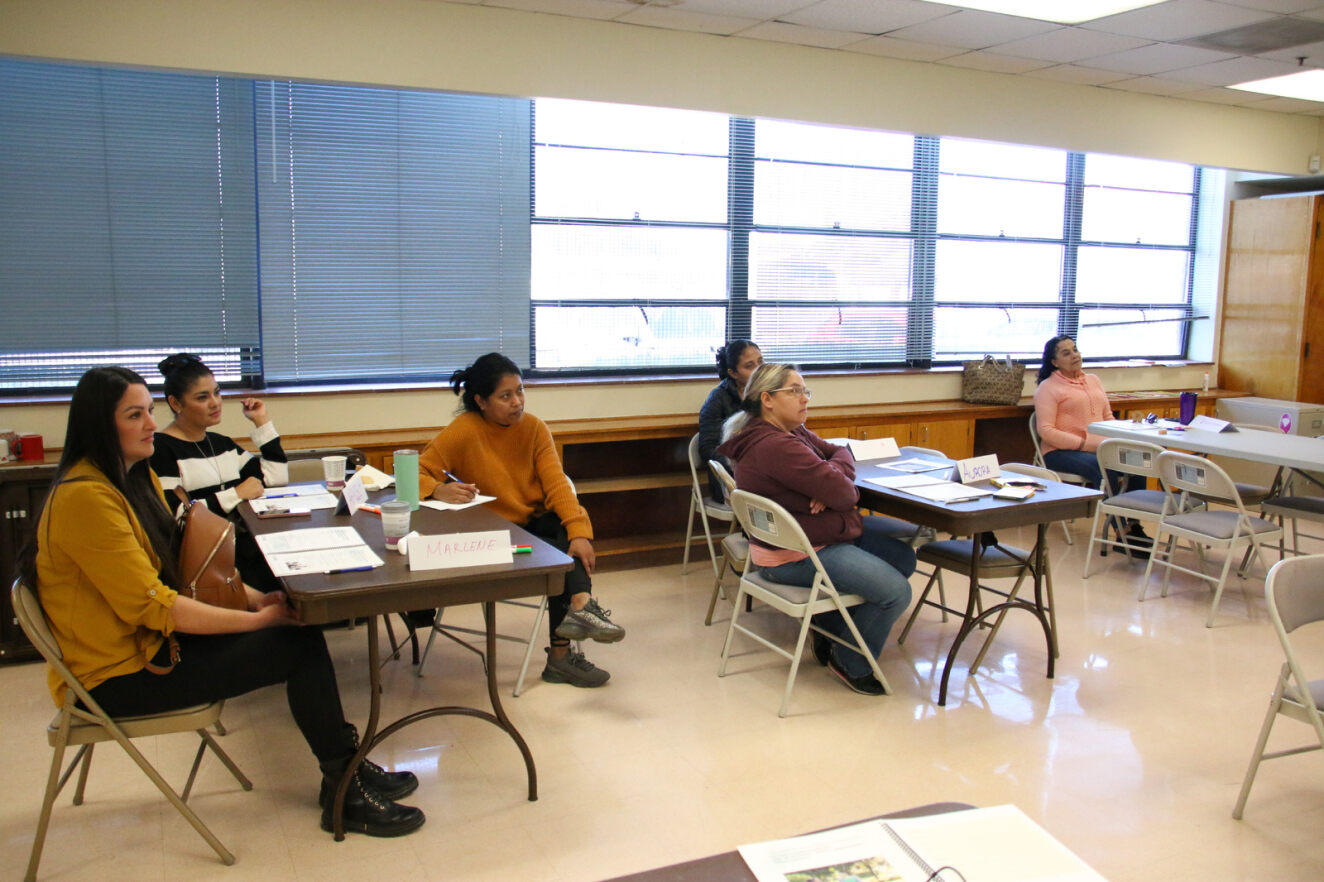 A group of parents listen attentively in a class at the Menlo FRC.