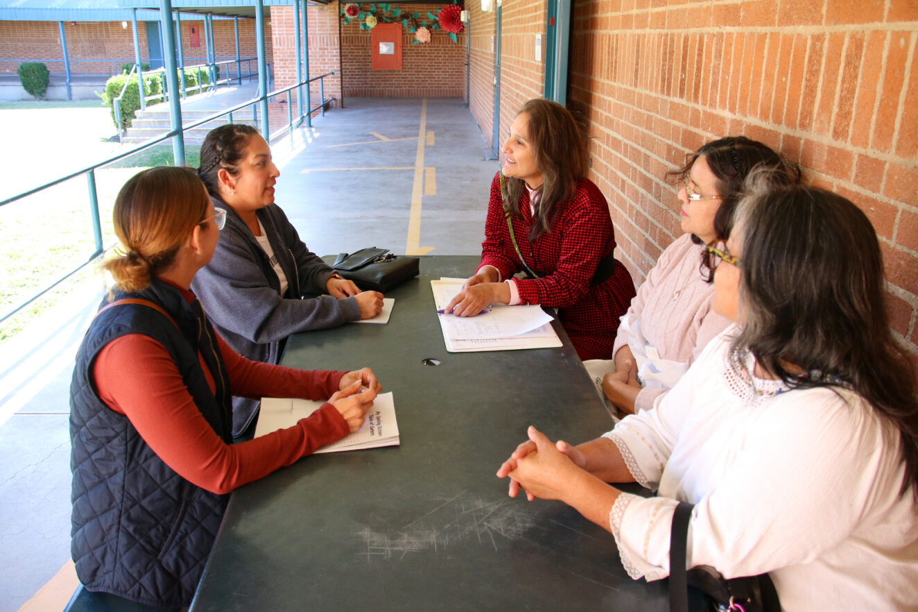 A group of parents talk at a table outside the Menlo FRC.