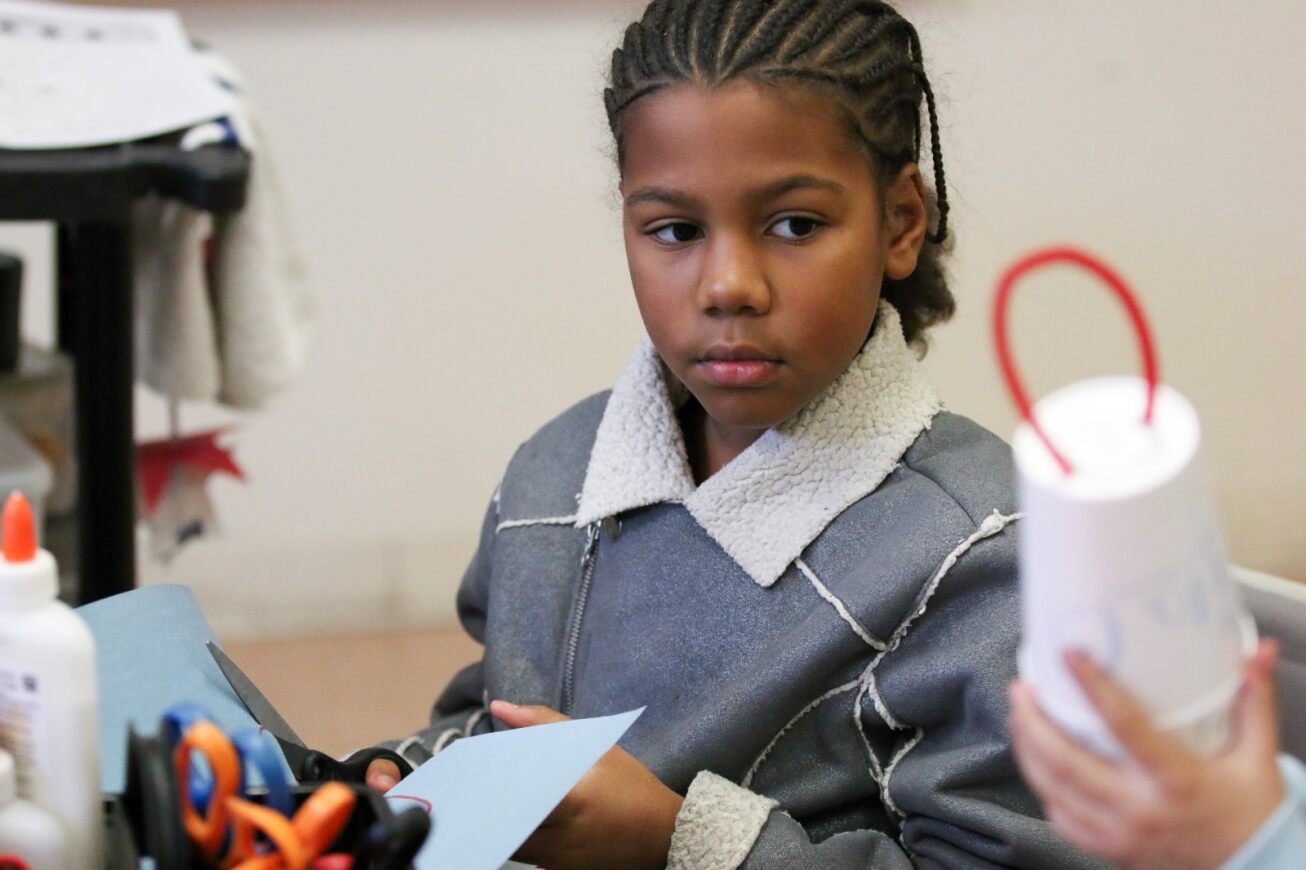 A student looks at another student's Liberty Bell craft.