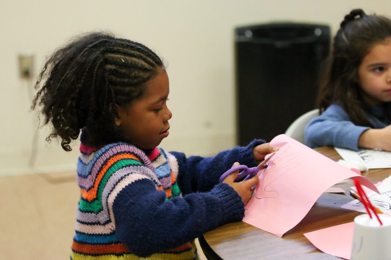 A student cuts out an outline of her hand.