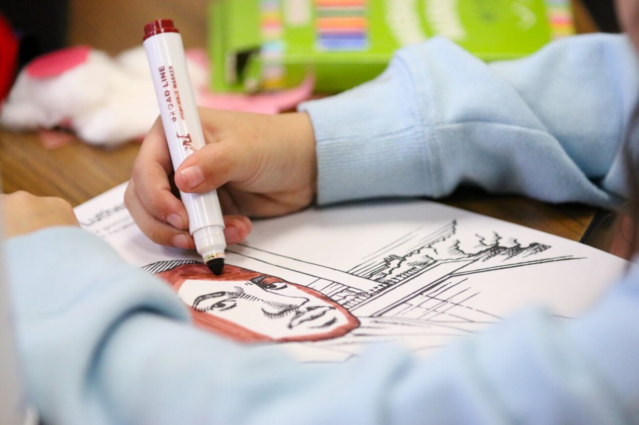 A student colors in a drawing of MLK Jr.