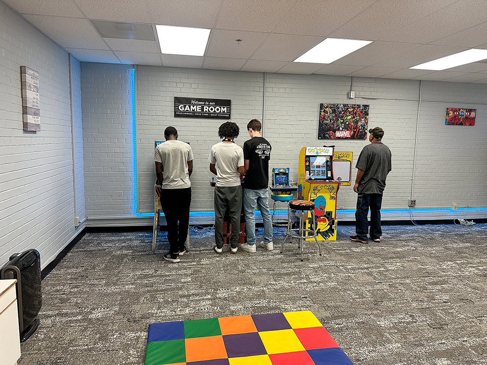 Students play arcade games in the game room of the FRC