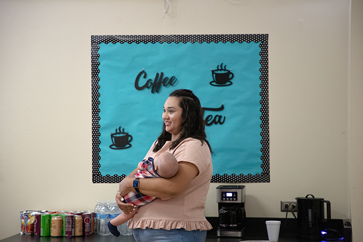 A woman stands holding her baby