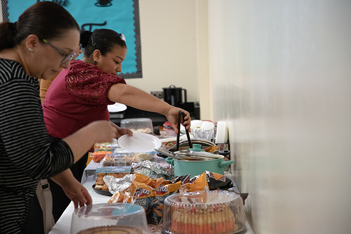 Women serve themselves food from a buffet table