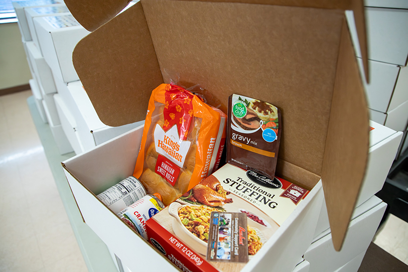 A Giving Box, filled with Hawaiian rolls, a packet of gravy, a box of stuffing and canned cranberry