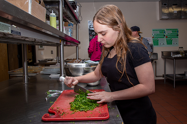 A teen girl chops up herbs