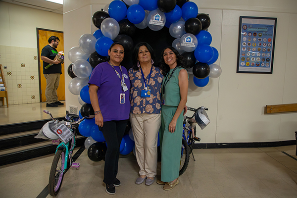 Three women stand in front of a balloon arch and bicycles