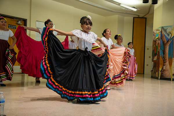 A group of little girls dance in their colorful folklorico dresses
