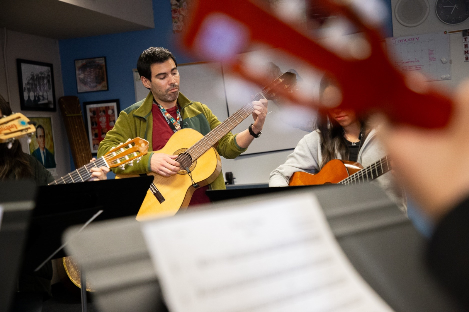 A mariachi teacher leads students on the guitar
