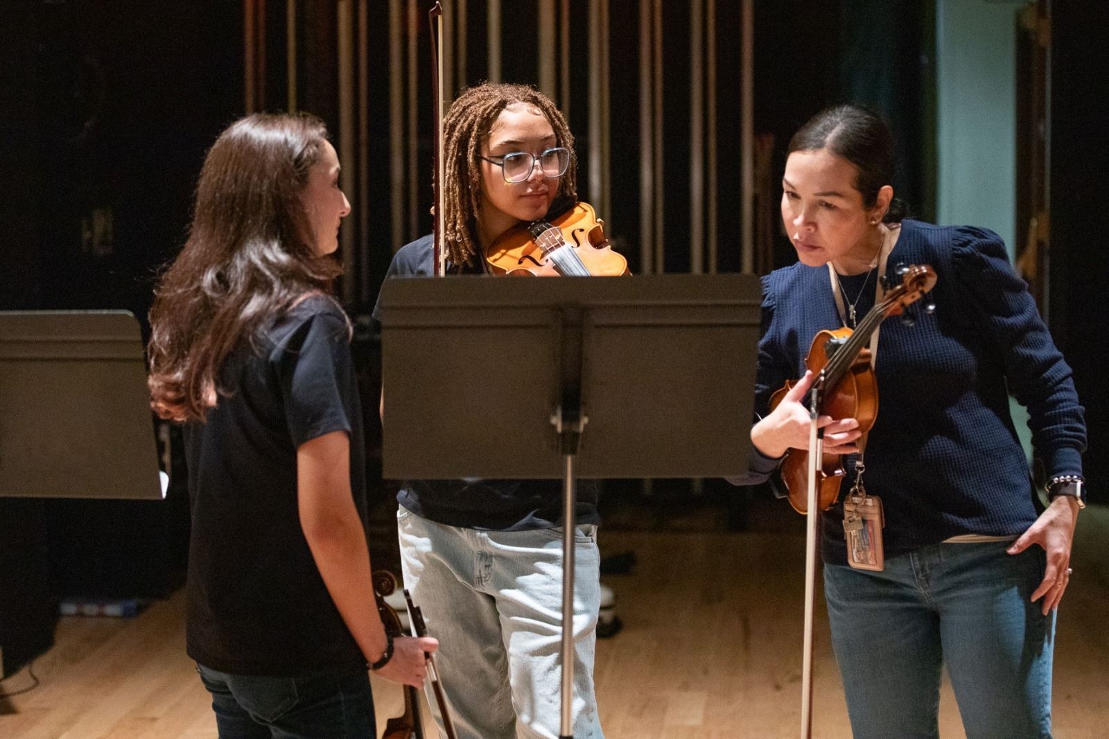 A teacher looks at sheet music with mariachi students