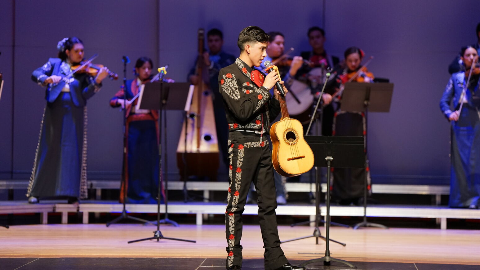A student gets ready for his solo, holding his guitar and a microphone