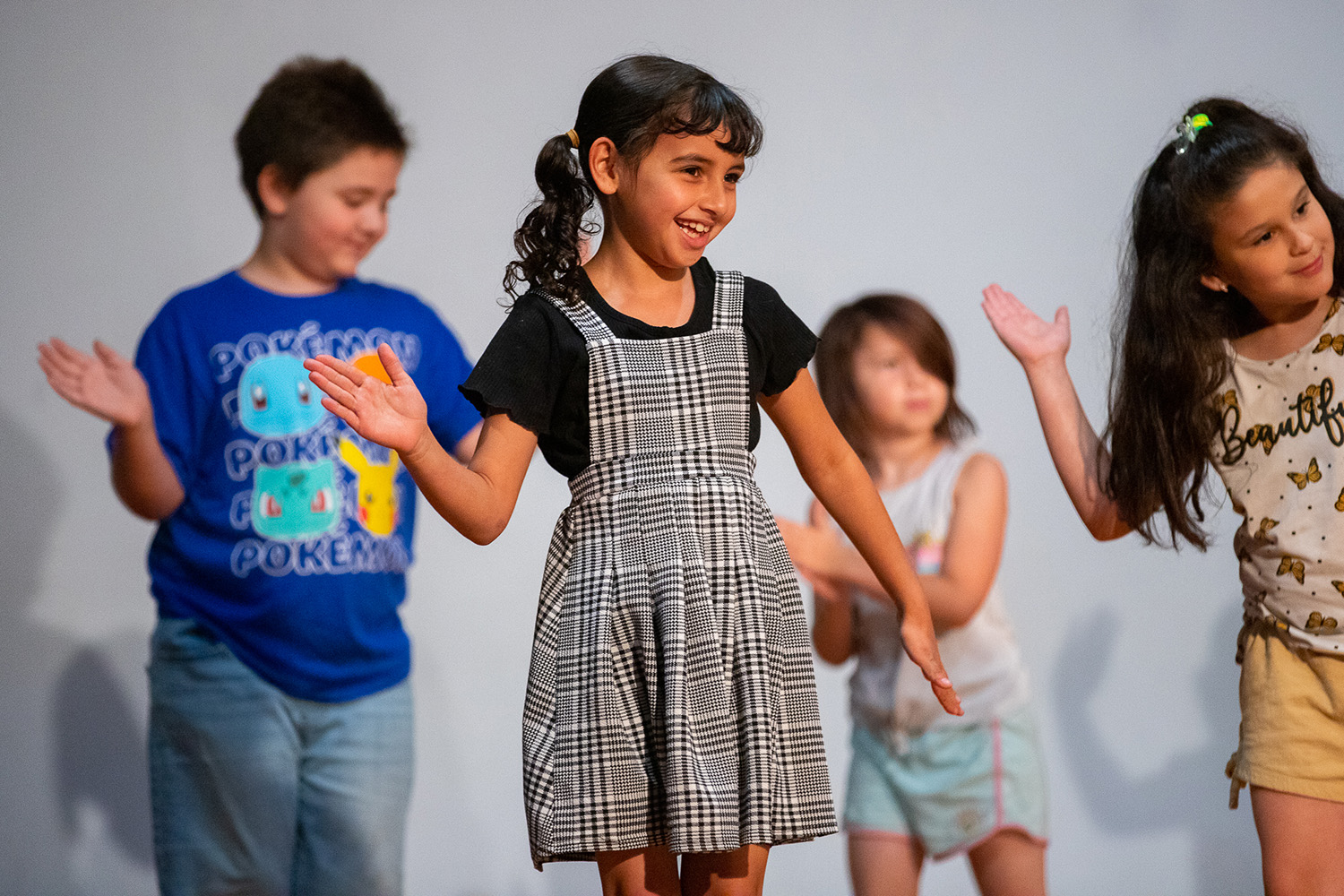 A student holds a pose with arms arching over her head.