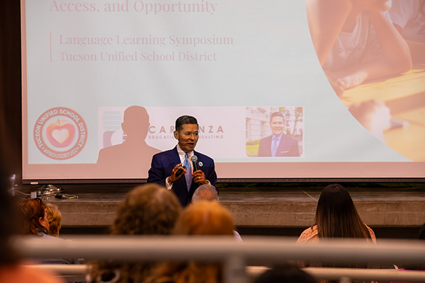 A man talks to the audience in front of a Powerpoint screen