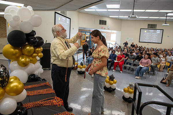 A man places a braided cord around a teen girl's neck