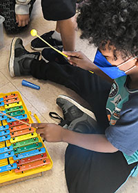 Young child playing xylophone.