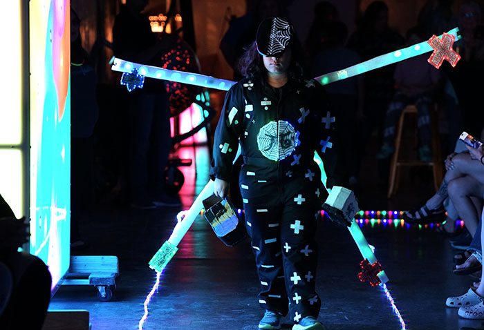 A boy in a light-up costume walks the runway