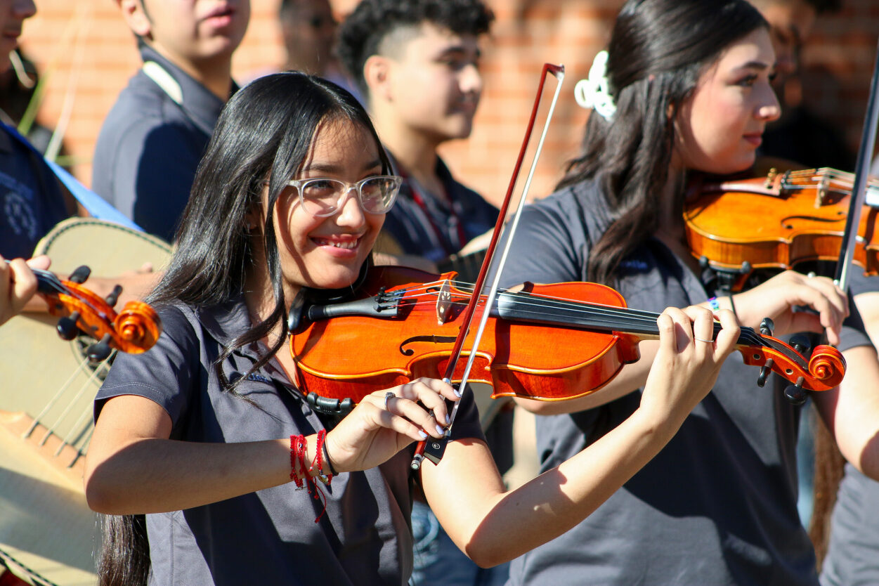 Students smile while playing violin