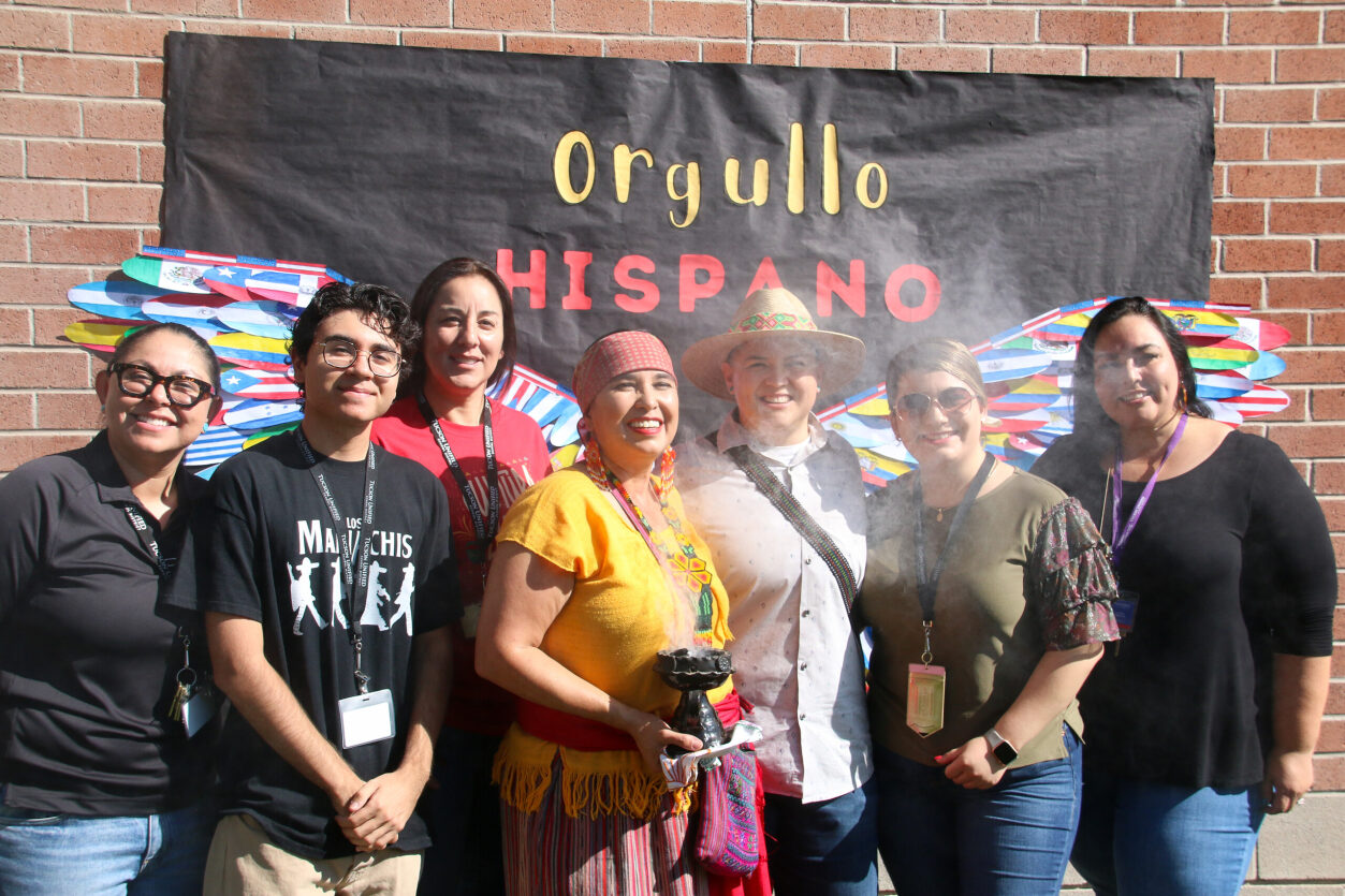 Mexican American Student Services staff stands in front of sign for Mes de la Cultura