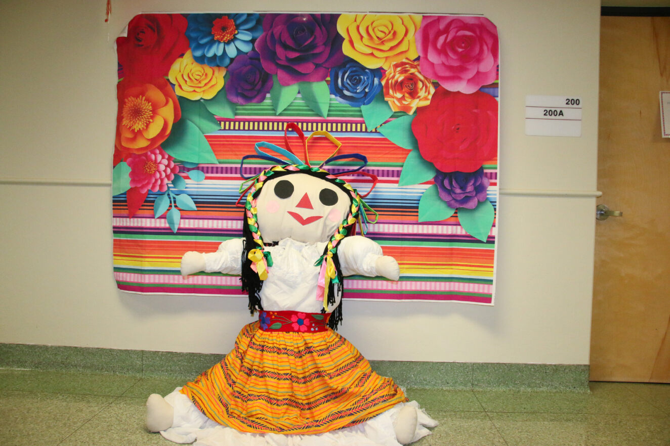 A Mexican rag doll (Maria doll) is on display with some Mexican artwork.