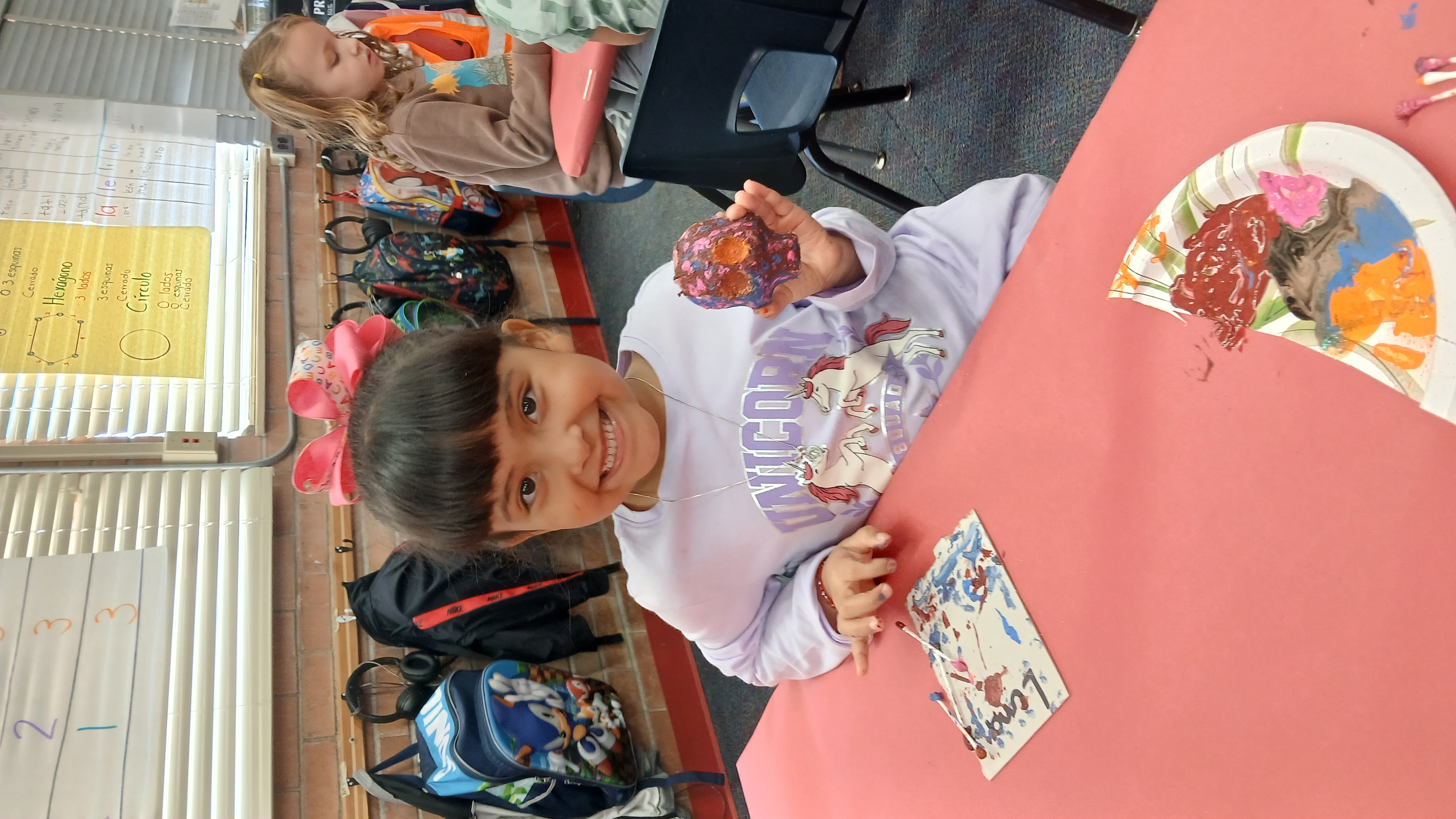 A woman in a blue dress kneels on the ground holding a vessel, while others stand around her