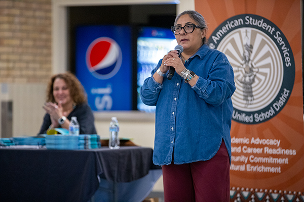 A woman with glasses speaks into a microphone