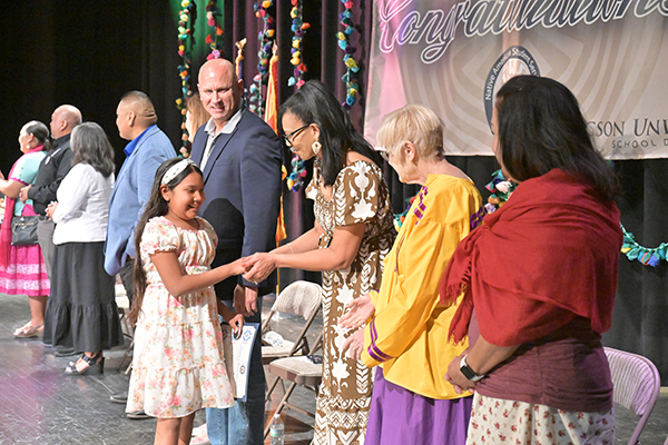 A little girl shakes hands with administrators on stage during the ceremony