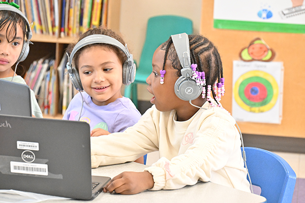 Three young girls look at their laptops