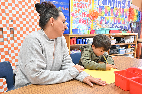 A woman helps a young student with his project
