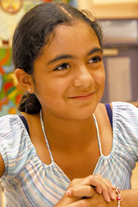 Girl with dark brown hair listens in a classroom. 