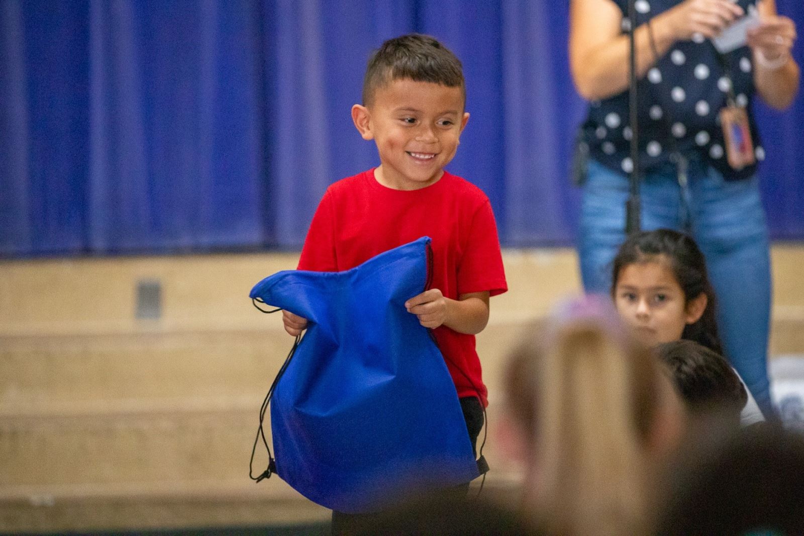 A boy smiles with his brand new backpack he just won!