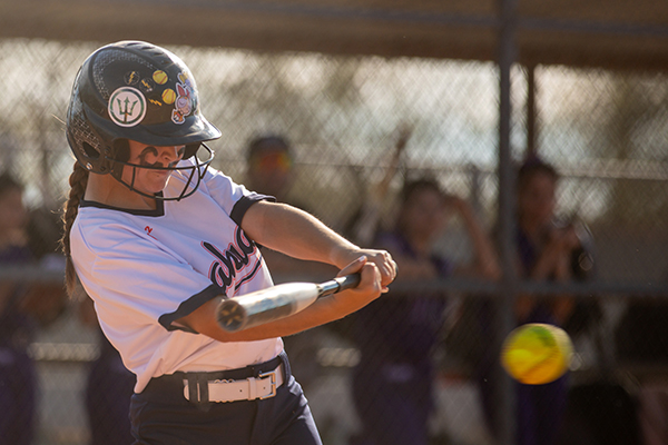 A girl swings a bat at a softball