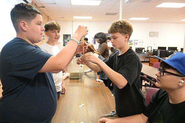 A group of high school boys build a tower with spaghetti