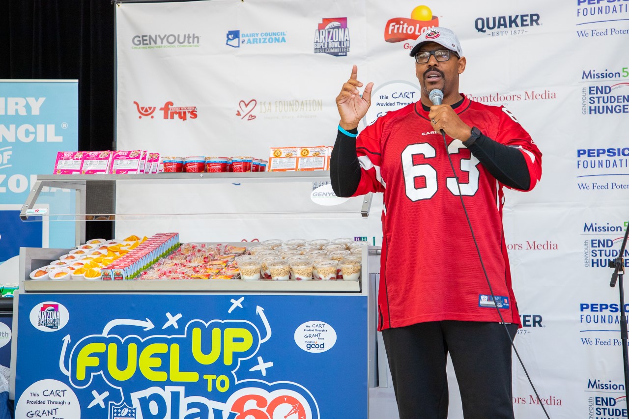 Former Arizona Cardinal Michael Bankston speaks in front of school meal donations from GENYOUth at Wright Elementary School.
