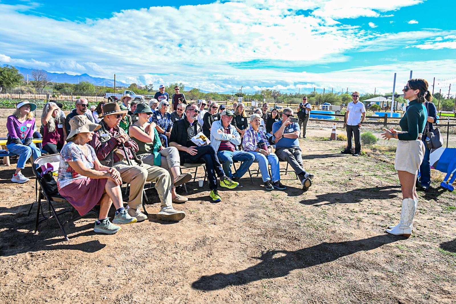 A group of people listens to an award presentation for John Brooks at Tucson Village Farm.