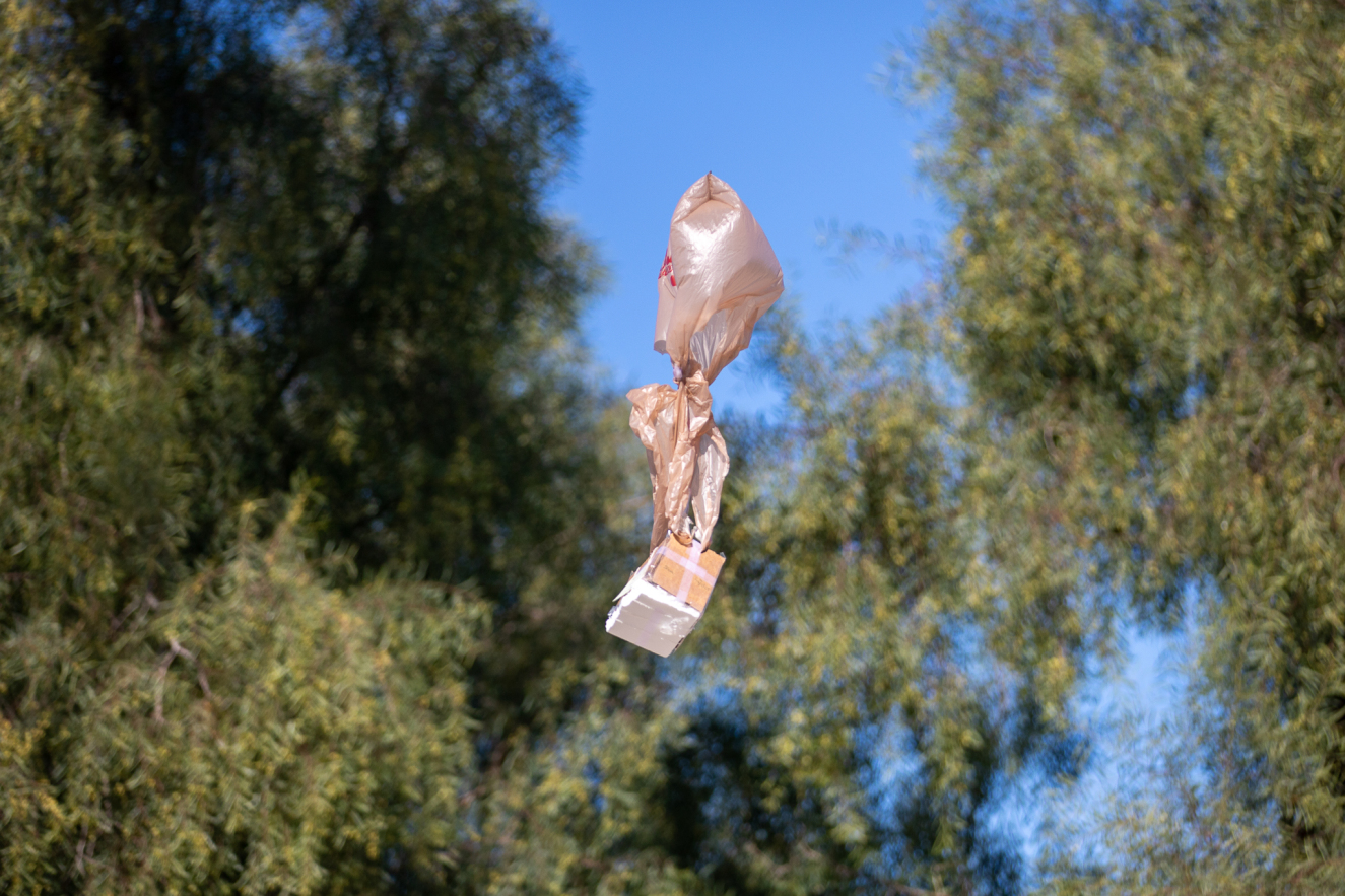 An egg stored safely in a box attached to a grocery bag falls from a fire truck.