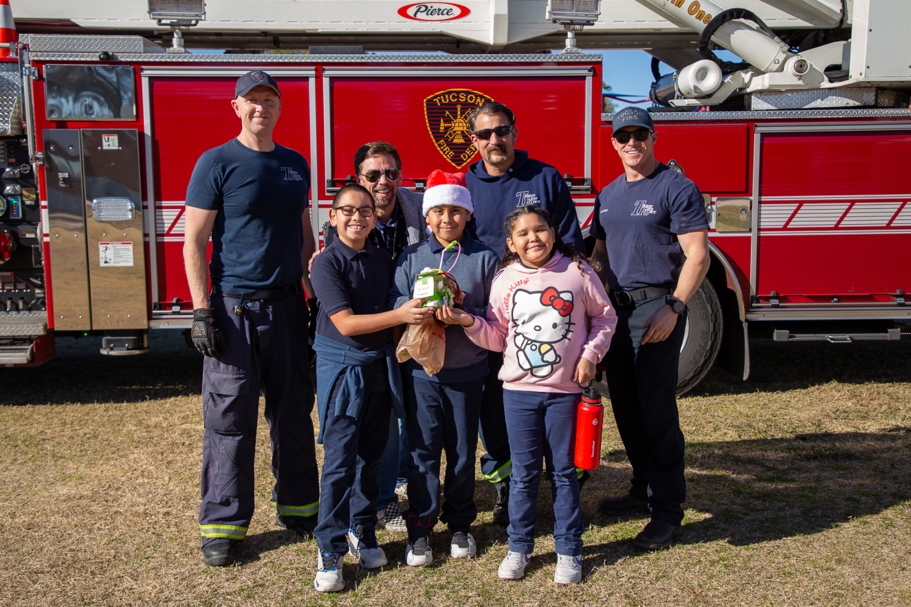 Robison students pose with Tucson firefighters in front of a fire truck.