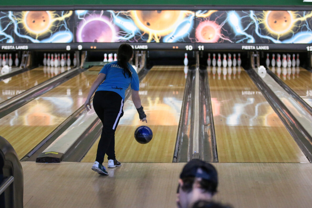 A girl in a blue shirt takes her turn in the bowling tournament.
