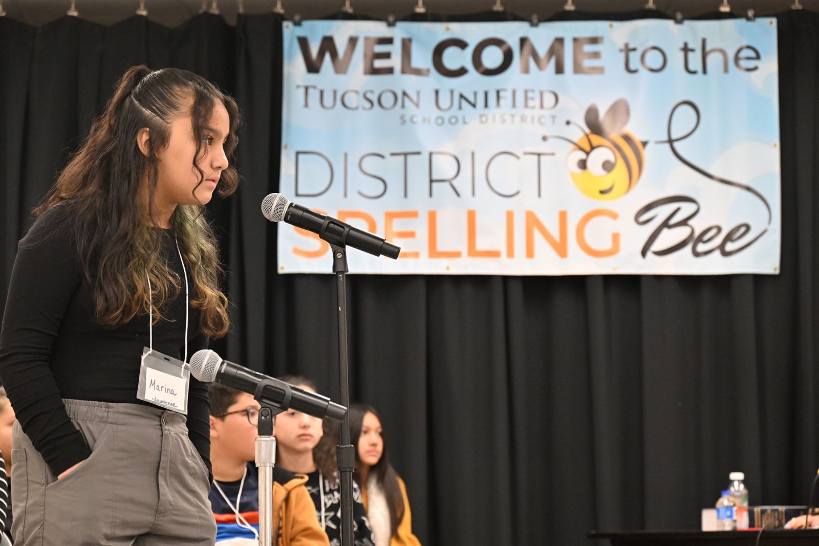 A girl goes up to the microphone to spell her word.